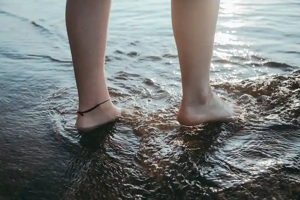 Girl legs on the water wearing black thread on a leg